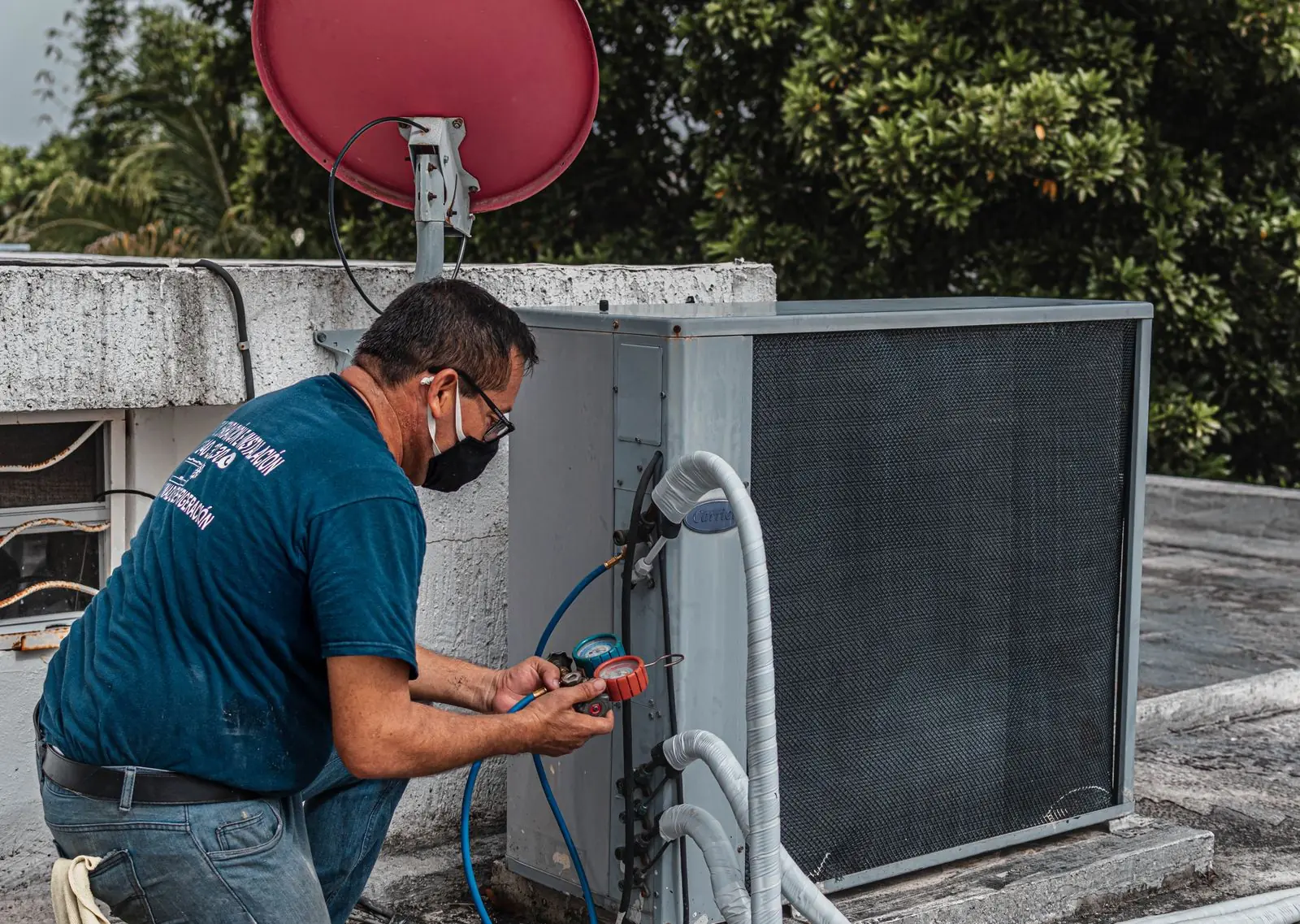 Técnico midiendo presiones con manómetros en una unidad exterior de aire acondicionado en una azotea