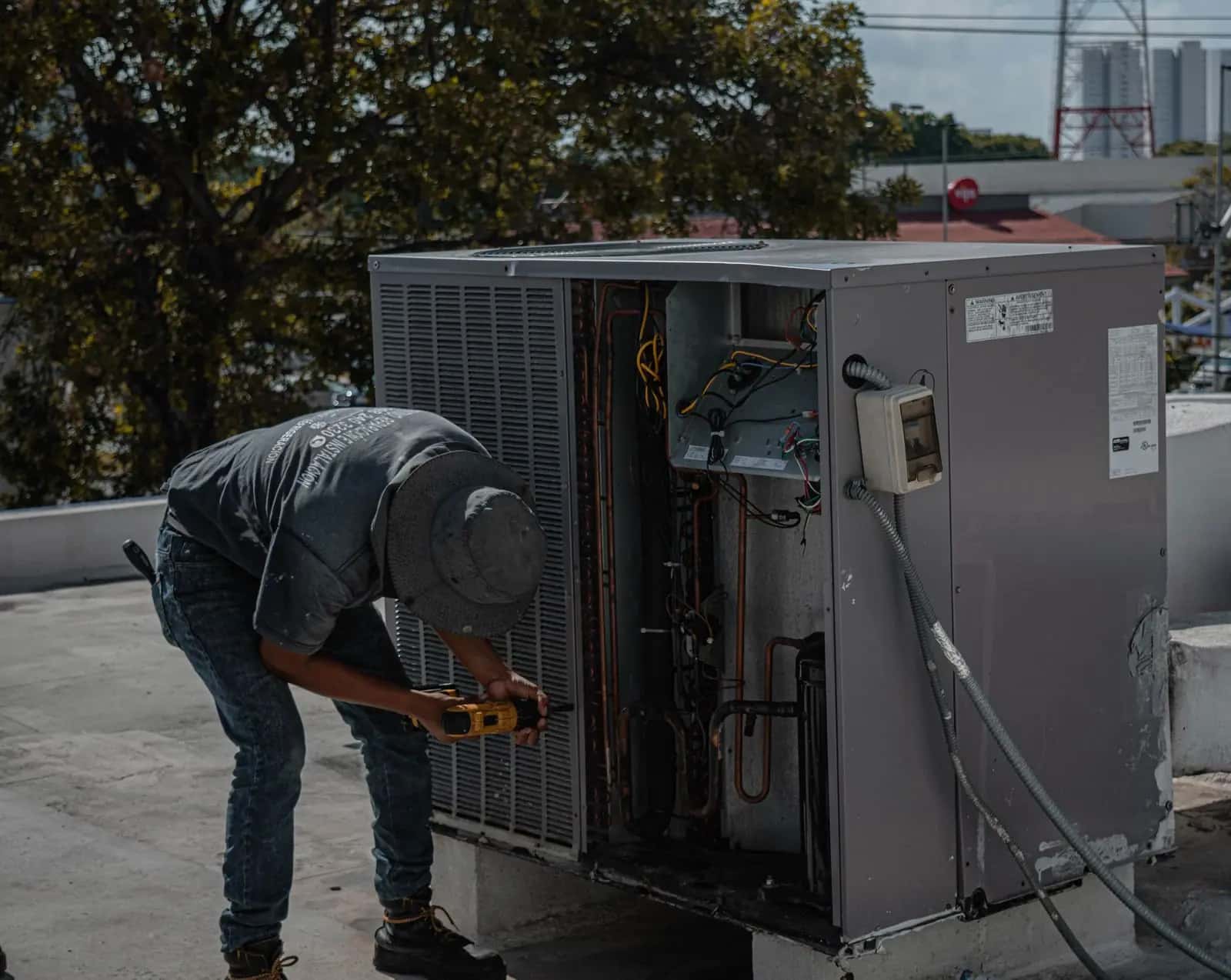 Técnico revisando el interior de una unidad exterior de climatización abierta en una azotea