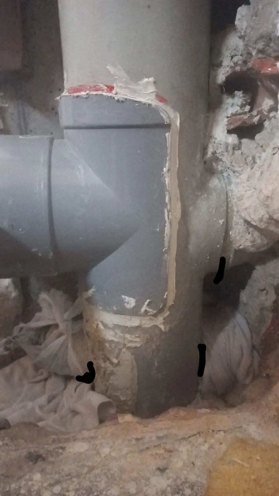 Bajante de PVC gris con injerto en T al descubierto dentro de una pared abierta