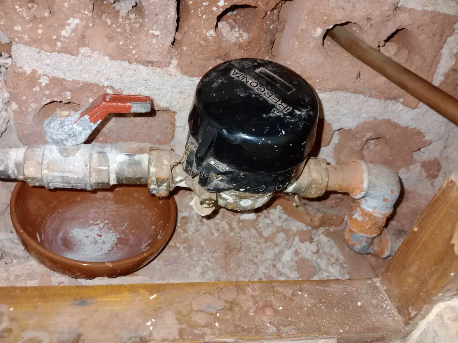 Contador de agua antiguo con llave de paso en una hornacina de ladrillo