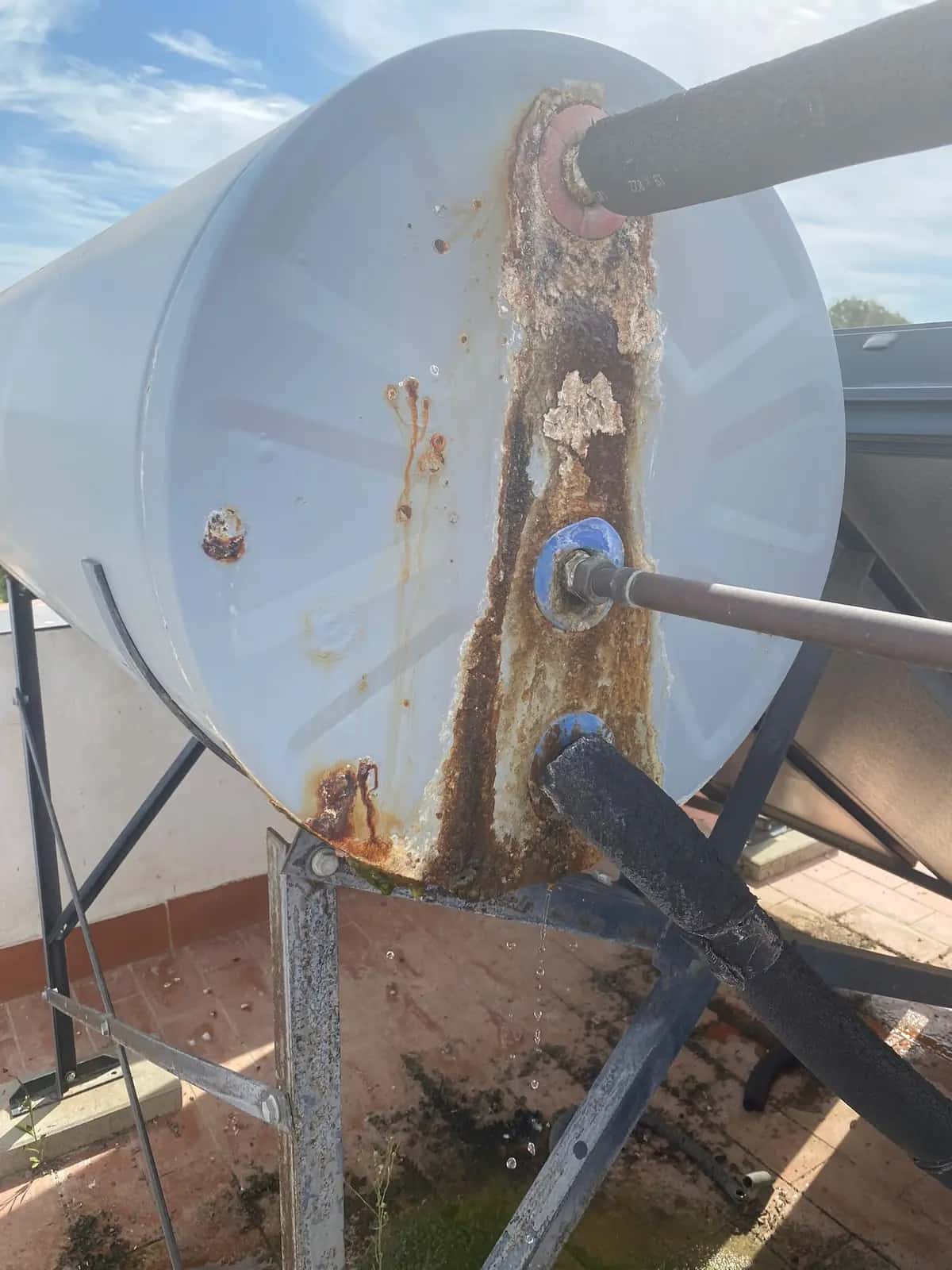 Depósito de agua caliente en una azotea con óxido y goteo por las conexiones