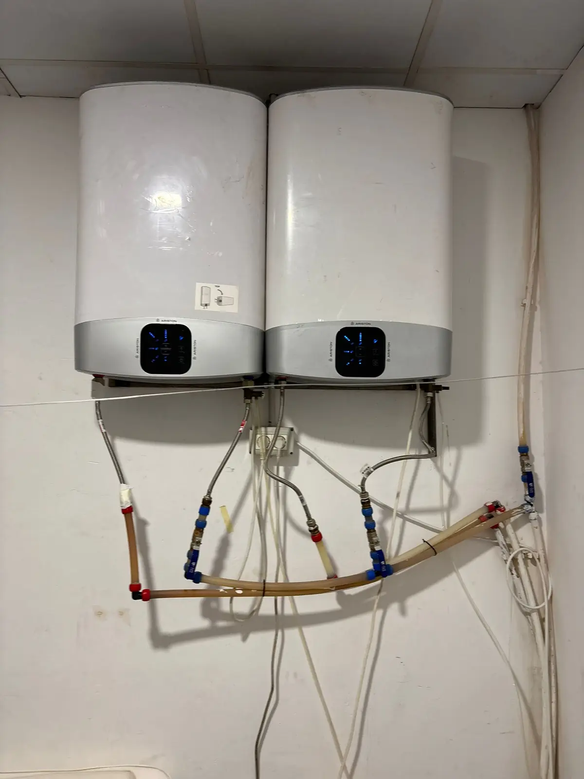Dos termos eléctricos instalados en la pared con tuberías de agua conectadas debajo