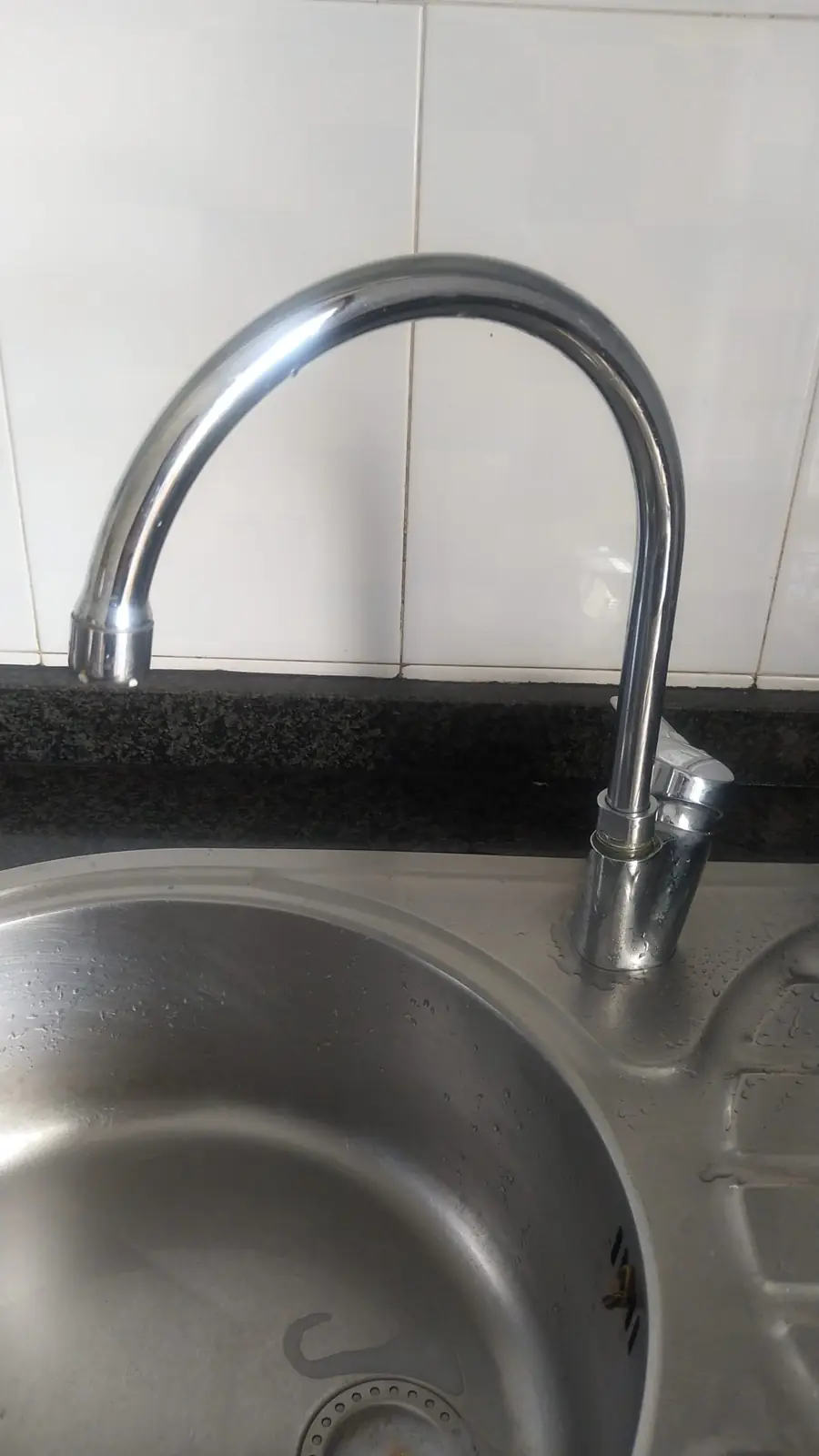 Grifo de cocina con caño alto sobre un fregadero redondo de acero inoxidable