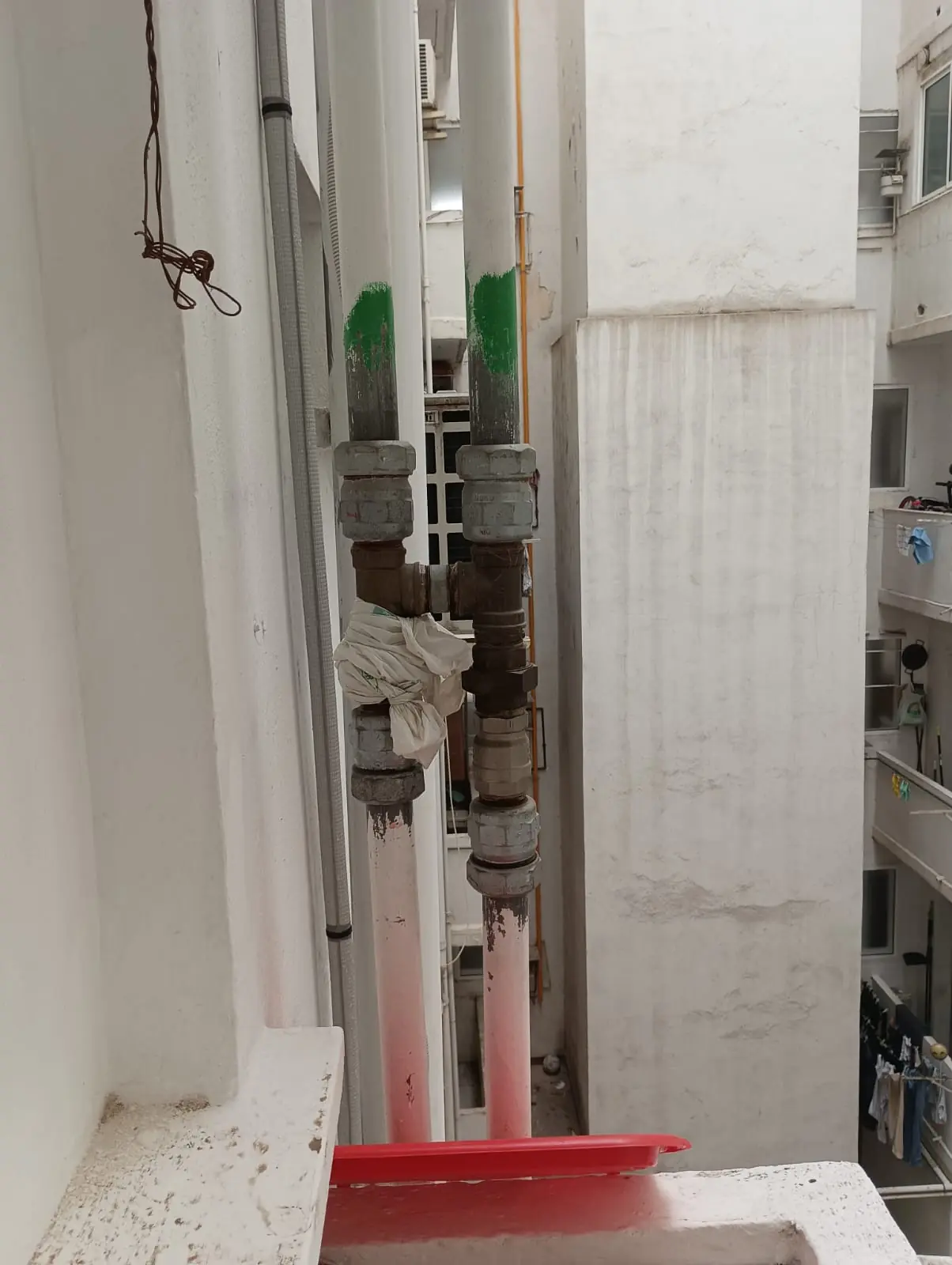 Montantes de agua verticales con tramo nuevo de tubería en un patio de luces