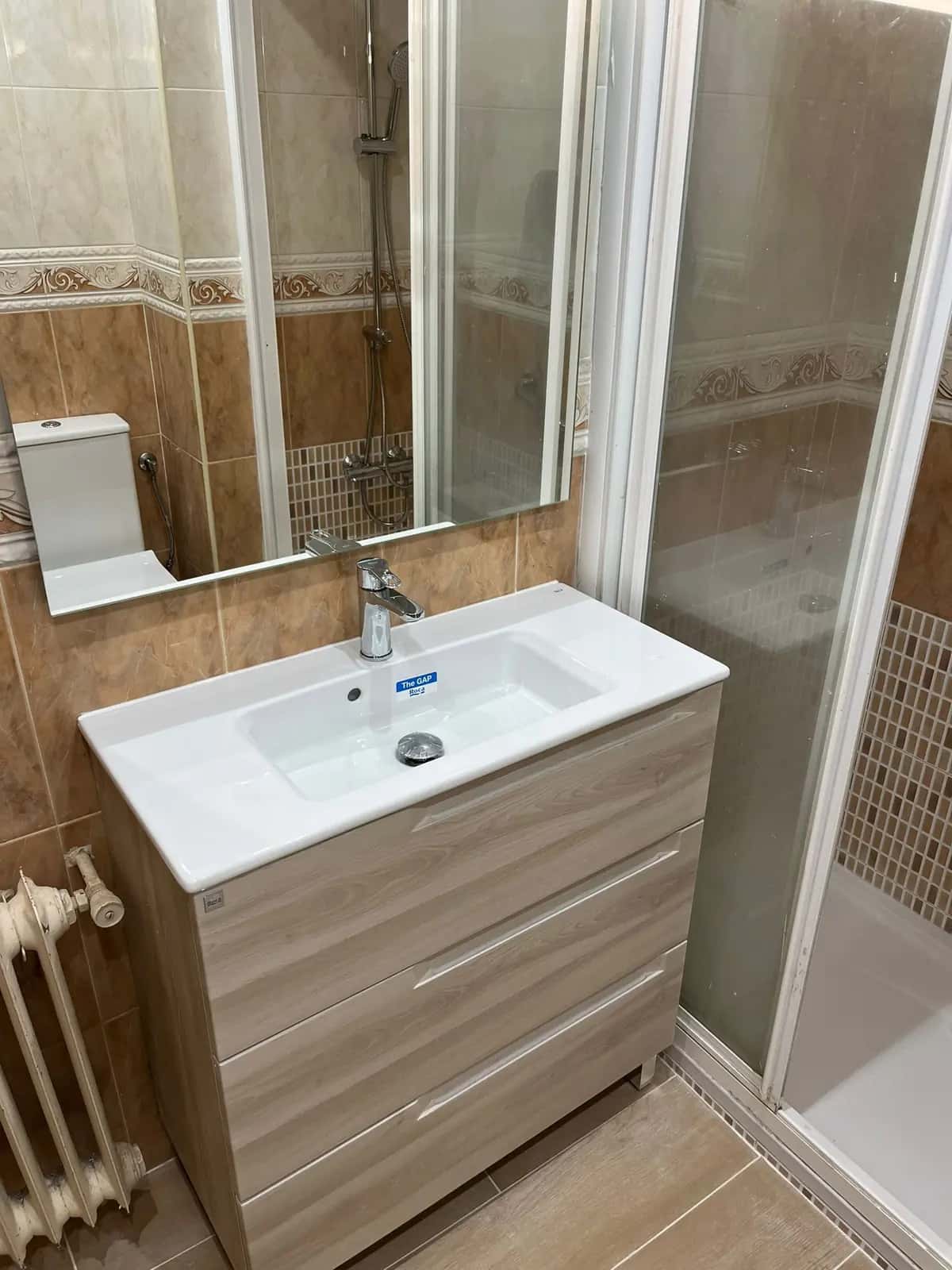 Mueble de lavabo de madera con espejo junto a una mampara de ducha