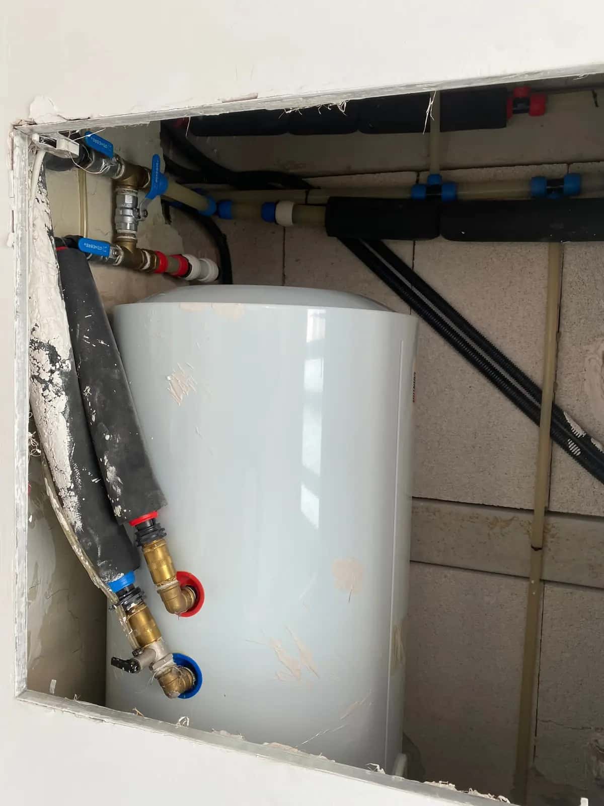 Termo eléctrico dentro de un hueco de pared con conexiones y llaves de paso nuevas