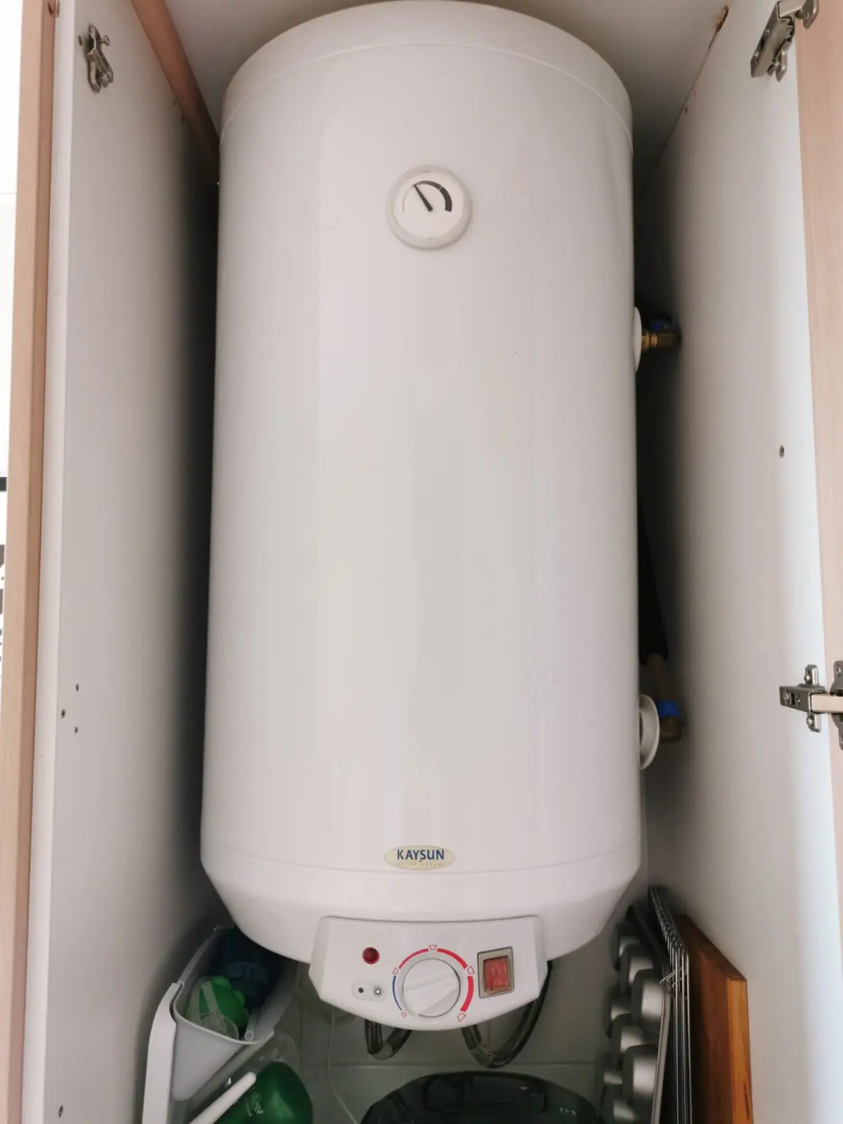 Termo eléctrico vertical instalado dentro de un armario con las puertas abiertas